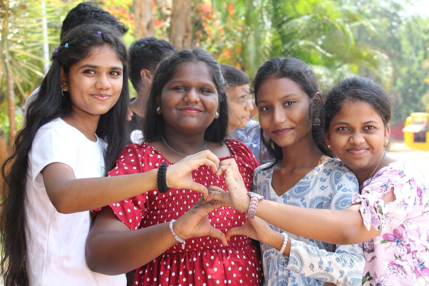 Four smiling campers making a heart with their hands