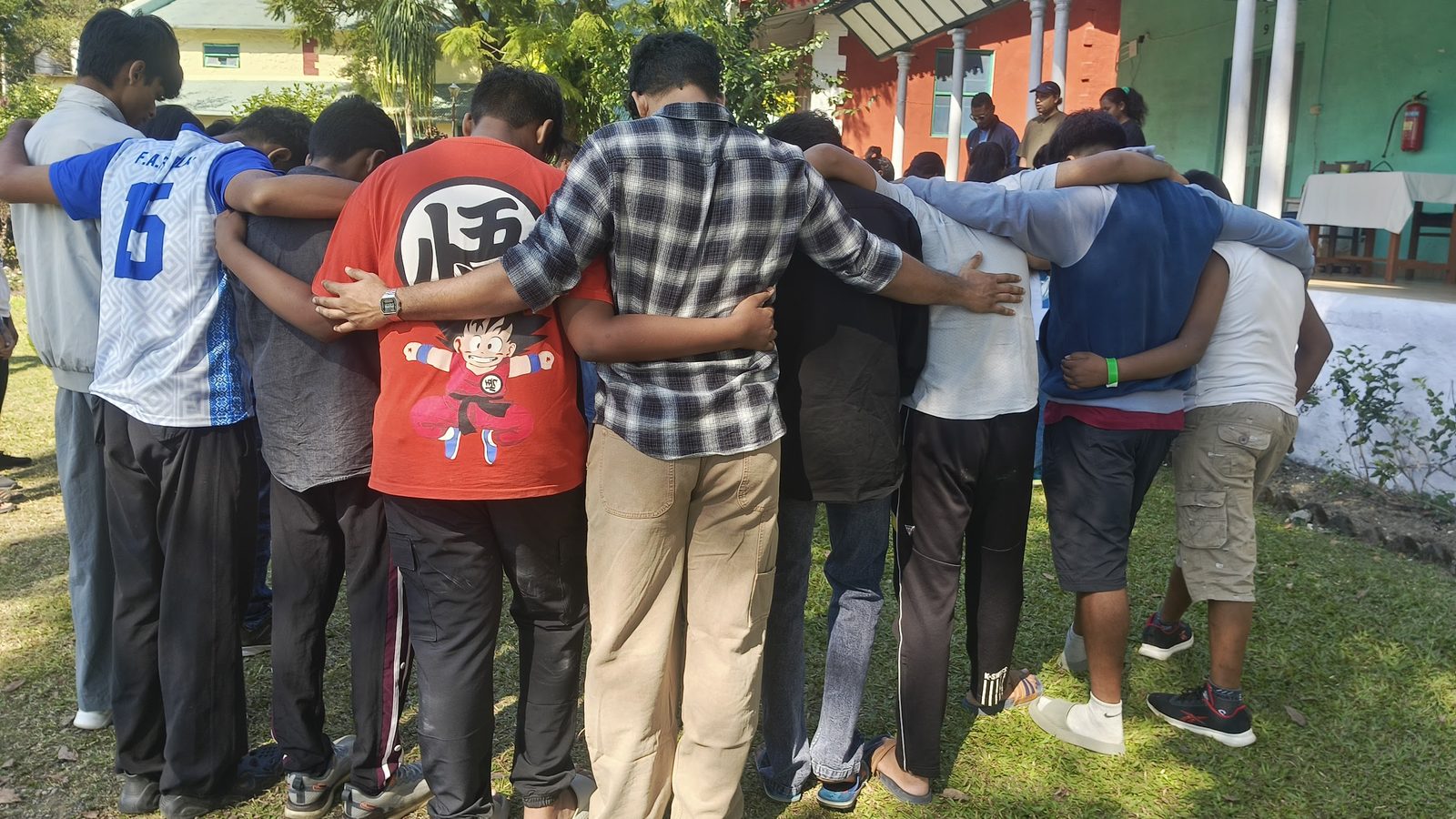 A group of campers in a huddle with arms around each other