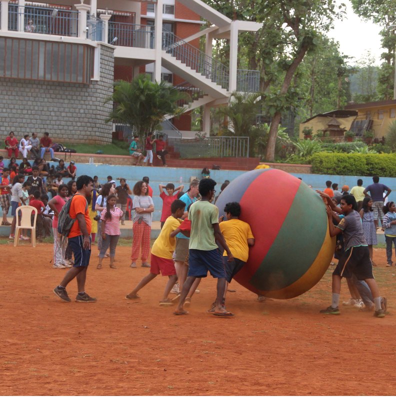 Campers pushing a giant earth ball across a field