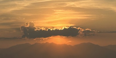 A sunset breaking through clouds above a mountain ridge